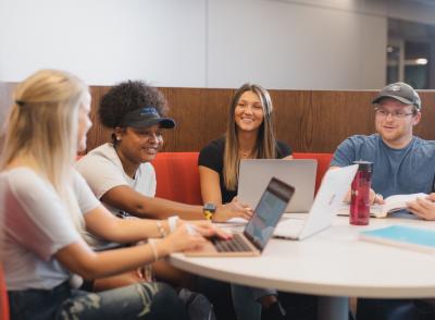 four students at a table with laptops