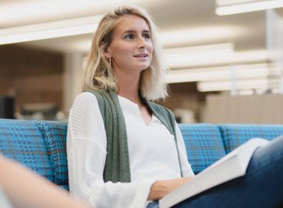 female student with open book in library